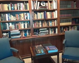 Pair of open arm chairs and a glimpse of the library shelves