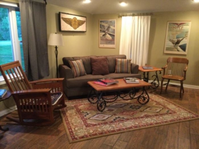 Sofa hide-a-bed, craftsman style rocking chair, arts and crafts style coffee table, oak mid century chair, World War II posters. The mosaic walk hanging is not included in this sale.
