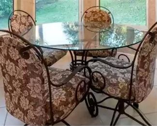 Round glass dinette table with metal base and 4 chairs on casters. Fabric matches the 2 bar stools.