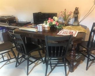Two different vintage tables and several vintage wood chairs.