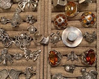 Sterling silver jewelry - on the left and scattered about the lower section on the right are animal-themed adjustable rings from Bali. The amber, top hat and house rings are from Russia. All 50% off!