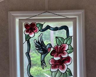 This is a stained glass hanging decor piece picturing a hummingbird getting nectar from a flower. 22x18 https://ctbids.com/#!/description/share/974605