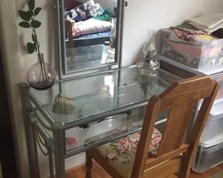 Metal and glass vanity table and wooden chair.