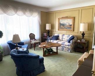 Formal living room 60” love seat cream with blue floral by Harden, 2 matching blue club chairs by Harden , one light gold/cream club chair by Harden, pair of matching Fine Arts of Grand Rapids square end tables and a cloverleaf shaped coffee table, also a small round side table and oil painting by German artist, Fritz Meyer.  Antique occasional chair with carved rosette and sage green upholstery. Everything is pristine in this immaculate nonsmoking and no pet home. 