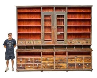 Monumental General Store Display Cabinet,  twenty-two drawers below open shelves, two glazed doors, paint remnants, porcelain accents, rising on bun feet
119"h x 139"w x 14.5"d
