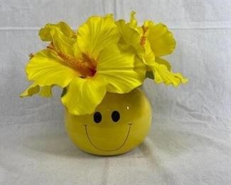 Yellow happy face vase with fake hibiscus flowers