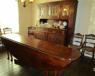 86" drop leaf dining table, hutch and four of six chairs. Oval when leaves are in place. Table is one of several styles sometimes referred to as a "Hunt Table" and used to distribute toddies, juleps or other early morning drinks before the hunt. 
