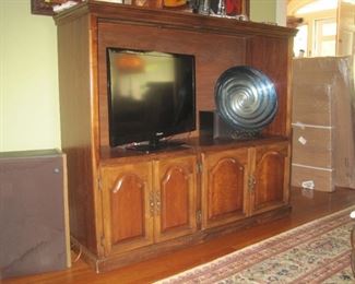Flatscreen TV,  cabinet and large bowl. 