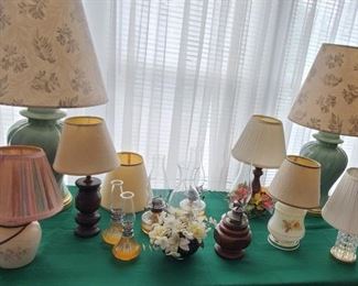 Assortment of oil lamps and electrical lights with shades.