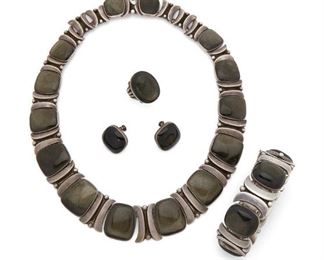 121
An Assembled Set Of Piedra Y Plata Obsidian Jewelry
Third-quarter 20th Century; Taxco, Mexico
Each stamped: Martinez / Piedra y Plata; Numbered: 75 / 230; Ring with indistinct marks
Designed by Felipe Martinez, comprising a necklace of graduated obsidian tablets flanked by polished silver curb links (16" L x 1" H), a bracelet of similar design (6.5" L x 1" W), a similar pair of screw-back earrings (.75" Dia.), and a similarly-styled ring (ring size 5.25), 5 pieces
235.5 grams gross
Estimate: $1,500 - $2,000