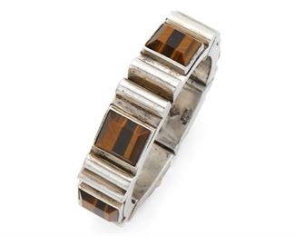 163
An Antonio Pineda Sterling Silver And Tiger's Eye Bracelet
Circa 1953-1979; Taxco, Mexico
Crown mark for Antonio Pineda; Further stamped: [indistinct eagle] / Hecho en Mexico / Silver / 970
A geometric hinged bracelet set with square pyramidal tiger's eye
7" L x .75" W
106.5 grams
Estimate: $600 - $800