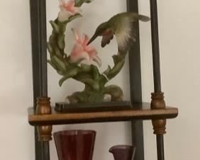 The wall cabinet that the hummingbirds are sitting on.