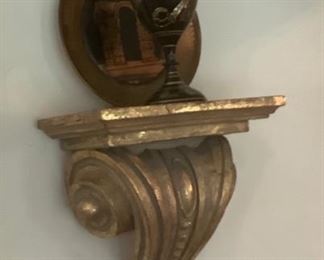 Close-up of one of the wall shelf’s and has copper small plate behind black vase.