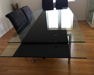 Incredibly beautiful contemporary Modern glass dining table with trundle leaves. Black glass down the center and sits atop silver chromed legs! Impressive.