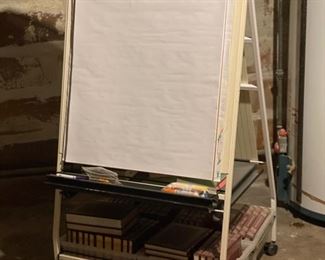Whiteboard easel with storage shelves.