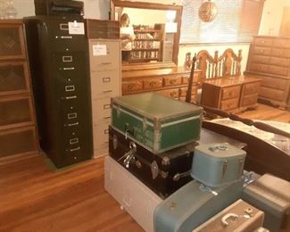 Foot lockers, old suitcases, file cabinets and bedroom set in background