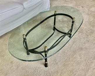 Oval glass topped coffee table with metal and brass base