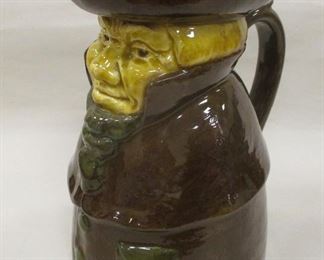 POTTERY TOBY JUG. BROWN AND YELLOW GLAZE WITH GREEN ACCENTS. NUMBERED 11620 III. 7.5" TALL. FACTORY GLAZE FLAW ON LEFT SHOULDER