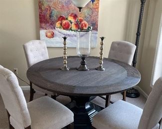 Round kitchen table with 4 side chairs (table has center pedestal), canvas print, floor lamp, and candle holders
