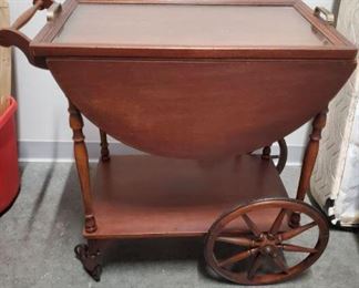 Vintage rolling wooden tea cart is darling and will add a touch of class to your next dinner party or look cute placed in any room. Tray has a glass top and lifts off. The rubber grip on the smaller wheels is separated from wheel.  Measures 31x17x30"https://ctbids.com/#!/description/share/1012659