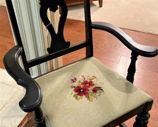 One black chair with arms with needlepoint seat