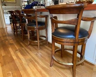 3 Woodbridge swivel counter stools. 37”H at back, 31-1/2” to top of arms and 24” seat. Wooden with leather seats.