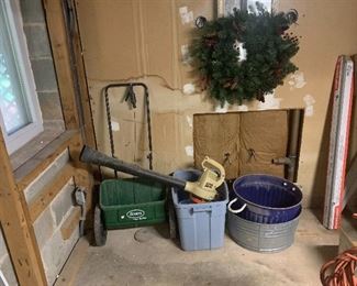 Lawn spreader, blower, galvanized pot and Christmas wreath.
