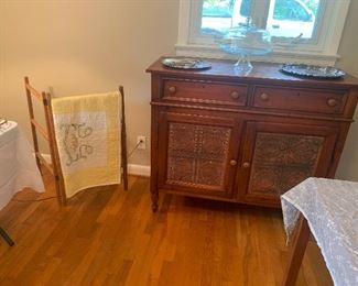 Vintage sideboard with tin panels. Vintage quilt hanger with handmade quilt.