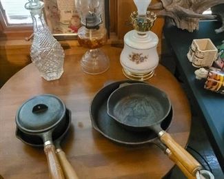 Vintage cast iron cookware with wooden handles, oil lamps