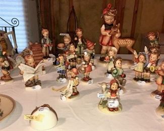 Hummel and Goebel figurines. Hummel annual plates from 1970s and 1980s (in original boxes). "Praying Angel" wall hanging, Hummel Latest News, Girl with Geese, Water Boy, North Winds, Baker Boy, Auf Wiederschauen. Large figurine is "Hummel Friends."