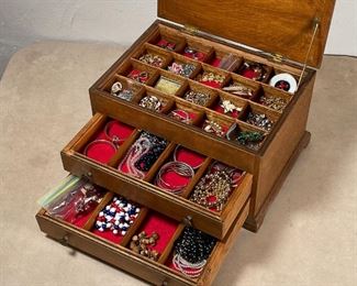 COLLECTION VINTAGE COSTUME JEWELRY | Wooden chest of costume jewelry, having a hinged lid with two lower drawers, with contents including earrings, necklaces, and bracelets, including beaded pieces, items by Monet, and others 