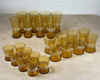(24pc) RETRO BLOWN GLASS | Vintage amber glasses with white ribbed banding, including 8 cordials, 8 low boys, and 8 tall glasses (h. 5-3/4 in.) [1 tall glass and 2 low glasses with flakes to rim, others appearing in overall good condition] 