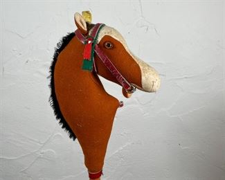 STEIFF HORSE TOY | Early Steiff horse riding toy, with a stuffed felt body, leather bridle and bit, on a wooden pole with red wheels; overall l. 42 x w. 7-1/2 in. [with yellow tag, missing left eye] 