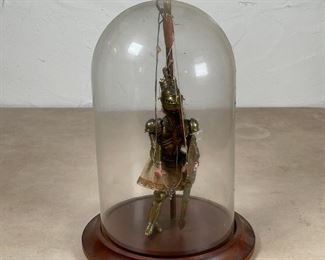 VINTAGE KNIGHT PUPPET | In a glass dome display case, a painted wooden stringed puppet of a knight with long hair dressed in suit of armor with articulating helmet; figure h. 6-3/4 in., dome h. 10-1/2 x dia. 7-3/4 in. 