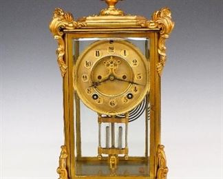 Ansonia Marquis Crystal Regulator - A turn of the century Ansonia "Marquis" model Crystal Regulator.  8-day time and strike movement with visible escapement, two part Brass dial and Arabic numerals.  Gilded Brass case with urn finial, beveled glasses and scrolled base inscribed "F. B. S. 1907".  Some wear, lacks rear door knob, running when cataloged.  16" high.  ESTIMATE $100-200
