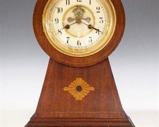 Waterbury Surrey Mantle Clock - An early 20th century Waterbury "Surrey" model mantle clock.  8-day time and strike movement with visible escapement, two part porcelain dial and Arabic numerals.  Shaped Mahogany case with inlaid detail, Brass bezel and feet.  Refinished case with minor wear, running when cataloged.  14 1/4" high.  ESTIMATE $200-300
