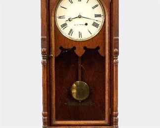 Seth Thomas Queen Anne Model Wall Clock - A late 19th century Seth Thomas "Queen Anne" model wall clock.  8-day weight driven time only movement with painted metal dial and Roman numerals.  Oak case with flat top, turned finals over a single long arched door flanked by turned half columns and shaped drop with spindled gallery.  Original dark finish with minor wear, slight dial wear, running when cataloged. 37" high.  ESTIMATE $400-600

