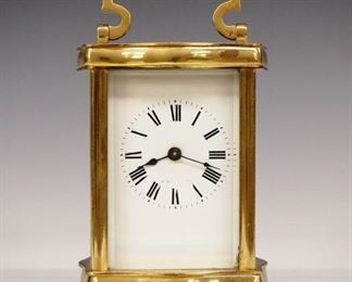 French Carriage Clock - An early 20th century French carriage clock.  8-day time only movement with platform escapement and porcelain dial with Roman numerals.  Shaped Brass case with fold down handle and beveled glasses.  Minor wear, large chip in side glass, running momentarily when cataloged.  5 1/4" high.  ESTIMATE $100-150
