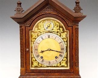W & H Bracket Clock - A late 19th century Winterhalder & Hofmeier bracket clock.  8-day time and strike movement with a Brass dial, Silvered chapter ring, Roman numerals, cast Brass spandrels and subsidiary Slow/Fast indicator dial.  Carved Oak case with pediment crest and three finials over a single door with arched glass, on a molded base with carved detail and turned feet.  Older refinishing with minor wear, running when cataloged.  17 1/2" high.