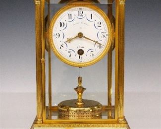 Claude Grivolas 400 Day Torsion Clock - An early 20th century Claude Grivolas 400 day clock.  400 day time only movement with convex porcelain dial, Arabic numerals and painted drape detail marked "Pendule 400 Jours, CG, Utilia" with gilded engine turned bezel and torsion pendulum.  Brass case with gilded detail having a flat molded top over a beveled glass door flanked by reeded Corinthian columns and beveled side and rear glasses on a molded base with scrolled skirt.  Fully marked on rear plate and base of pendulum with matching "2338" serial numbers.  Very good condition with slight wear, mismatched Grivolis dial, running when cataloged.  11 1/4" high.