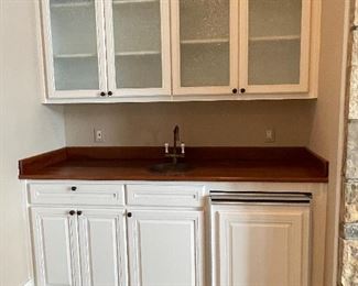 Wet bar:  77” wide wooden counter with copper sink, Sub Zero min-refrigerator with ice maker , upper and lower cabinets with frosted doors