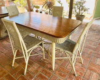 Tiger oak and wicker dining table with four high back white wicker chairs.