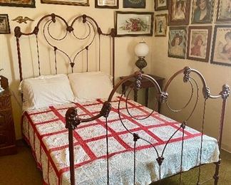Red cast iron double/full bed with a hand made red and white memory quilt