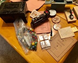 Old tin money box, marbles, Girl Scout foldable cup, souvenir penny paperweights, Book: History of Nails Creek Baptist Church and map Mr. Gilmore’s official city map of greater Atlanta. Tin wind up  locomotive. 