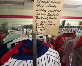 Costume racks are organized by type with signs.