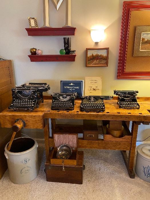 Corona and Underwood typewriters, primitive work bench, crocks, wooden storage boxes.  Rural scene framed canvas.