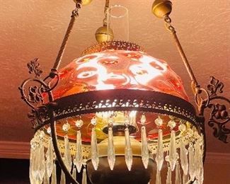 #33- NOW $275 was $350 • Victorian hanging light fixture fitted with a Domical bullseye  cranberry shade mounted on brass with dangling crystal • 34high 18across