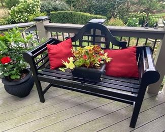 Beautiful black wood bench with throw pillows and pretty potted flowers!