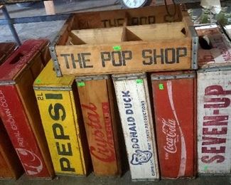 Vintage wooden cola crates including Coca Cola, Pepsi, Seven-Up, RC, Double Cola, The Pop Shop, Crystal, and Donald Duck. 