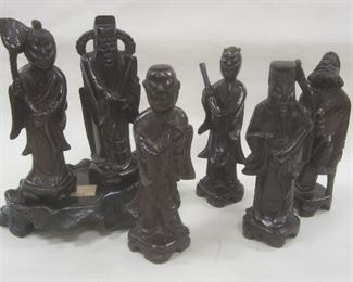 SET OF SEVEN CHINESE CARVED WOOD IMMORTAL FIGURES AND ONE CARVED WOOD STAND. ONE CHIP. 4.75" TALL